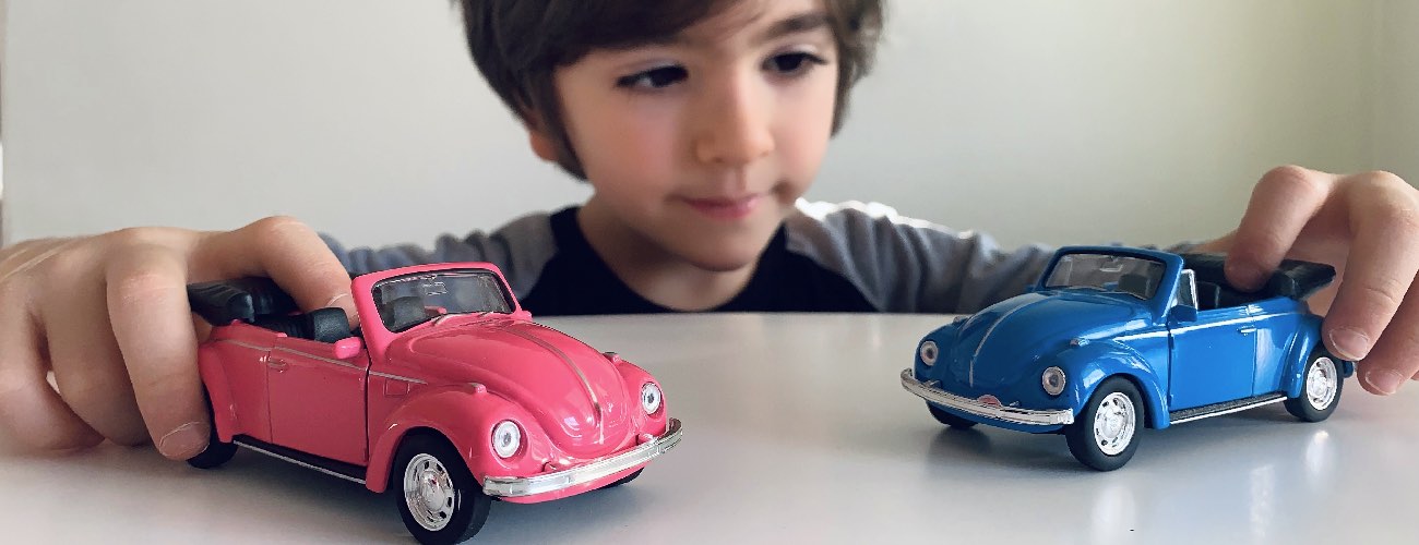 photo of a boy playing with 2 cars