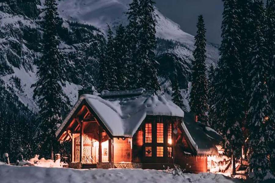 Boende lodge Järven, trästuga i Söldens alpnatur, ljuset från stugan lyser upp i vinternatten.