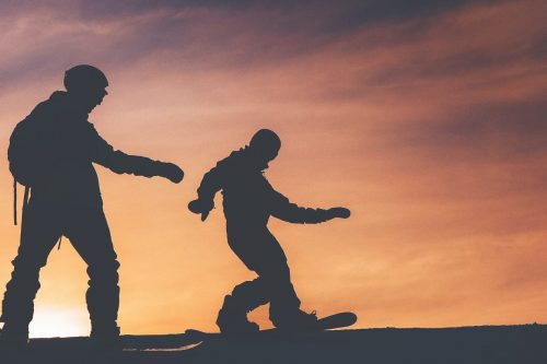 Två snowboardåkare som åker i skymningen